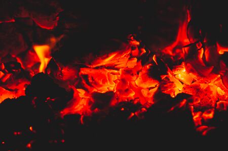 Beautiful red bright coals of bonfire. Close-up. Black background. Horizontal photo. Outdoors. Fading beautiful fire. Warm evening. Embers emit beautiful, red, breathtaking glow in dark.の写真素材