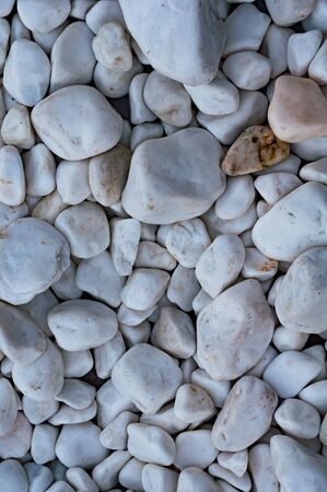 Background from rounded beautiful white pebbles. Sea pebbles. Decorative element. Design flower beds garden paths. Vertical photo. Closeup. Natural stone texture. Riverbank. Beach.の写真素材