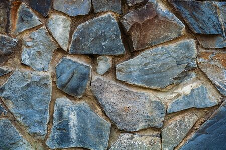 background from a wall erected from roughly treated brown and gray granite stones.の写真素材