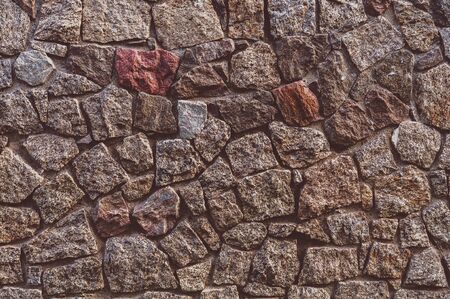 Old darkened from time to time wall with rough granite stonesの写真素材