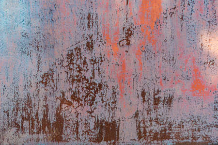 Rusty metal background with old red peeling cracked paint, atmospheric impact, outdoors, horizontal photo. Close-up.の写真素材