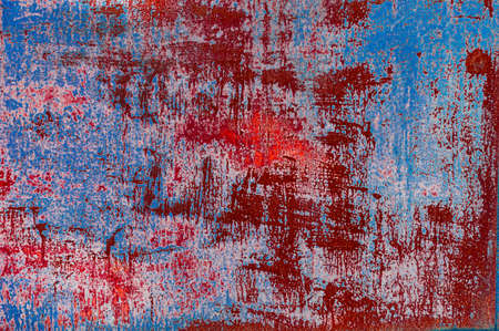 Bright colorful background from rusty metal with old blue and red shabby cracked paint, atmospheric impact, outdoors, horizontal photo, close-up.の写真素材