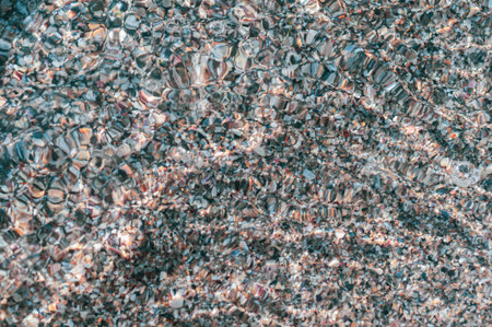 Blurred background surface sea water, view through troubled water to beautiful small pebbles,...
