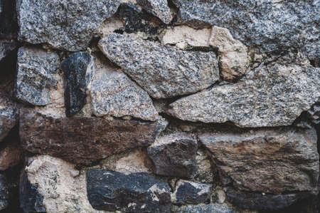 Wall with large stone, textured background close-up. Granite stones with moss and lichen, rough old surface, atmospheric exposure, outdoors. Horizontal photographyの写真素材