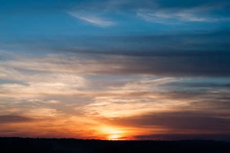 Colorful sunset, bright reflection warm sun rays illuminates dark cloudy sky. Outdoors. Horizontal photographyの写真素材