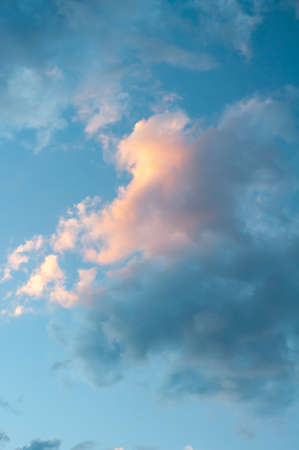 Bright blue sky, white translucent feathery clouds, reflections warm rays setting sun, swirls strong gust wind, outdoors. Horizontal photographyの写真素材