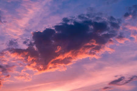 Bright blue sky, white translucent feathery clouds, reflections warm rays setting sun, swirls strong gust wind, outdoors. Horizontal photographyの写真素材