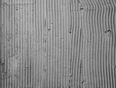 Texture applied tile adhesive on wall, ribbed concrete background close-up, building materialの写真素材