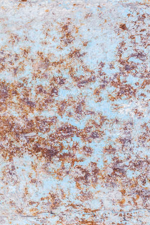Rusty metal surface, not painted, oxidized rough texture, brown rust with peeling blue paint, outdoors, vertical close-up photo.の写真素材