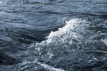 Background, top view, rapid flow river with dark blue water and white foam waves.の写真素材