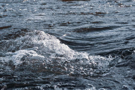 Background, top view, rapid flow river with dark blue water and white foam waves.の写真素材