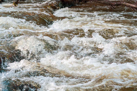 Background, top view, rapid flow river with dark blue water and white foam waves.の写真素材
