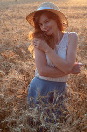 Happy woman enjoying life in field with flowers. Beauty nature, blue cloudy sky and colorful field with flowers. Outdoor lifestyle. Freedom concept. Woman in summer fieldの写真素材