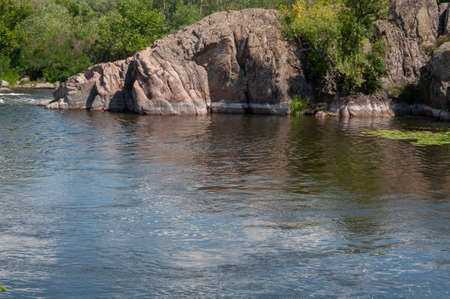 Large granite stones, trees growing on shore, river flowing among granite rocks, nature outdoorsの写真素材