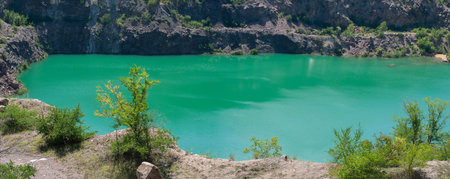 Flooded granite quarry, emerald green water saturated with radon, vegetated shores