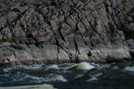 Sun glare on surface water and smooth stones at bottom stream, background. Transparent water in river with rocky bottom, fast flow. Nature outdoors close upの写真素材