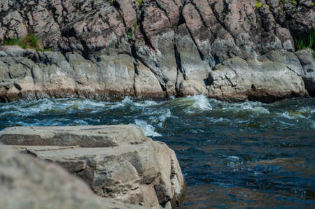 rocky bank a mountain river overgrown with moss bushes and trees, fast muddy stream water, nature outdoorsの写真素材