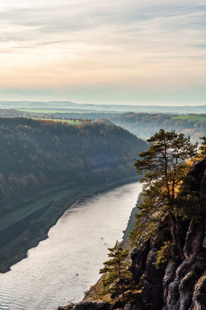 Water flows through mountainous terrain with trees under the sky and clouds