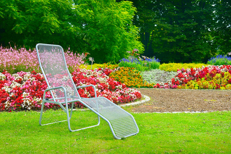 deckchair in park next to the flower bedの写真素材