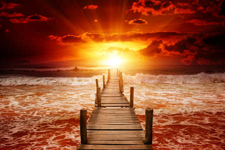 Pier for boats into the sea. Bright sunrise over the ocean. Fantastic collage.の写真素材