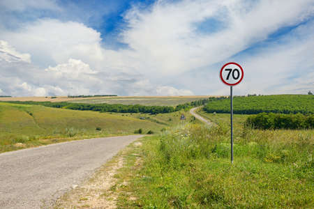 Road sign limiting speed on a country road. Bright sunny day.の写真素材