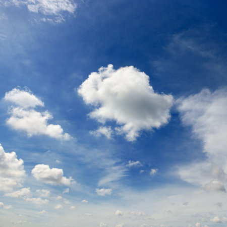 White cumulus clouds on the background of an epic dark blue sky.