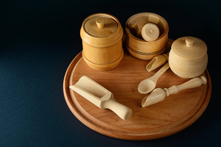 Wooden containers for products, spoon, cup, pestle, mortar on wooden board. Free space for text. Black background.の写真素材