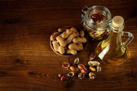 Peanut oil in bottle and dry nuts on wooden table. Top view. Free space for text.の写真素材