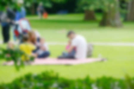 Blurred image of young family with children in summer park.の写真素材