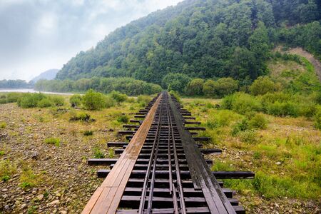 Old wooden railway bridge with footpath in mountain river valleyの写真素材