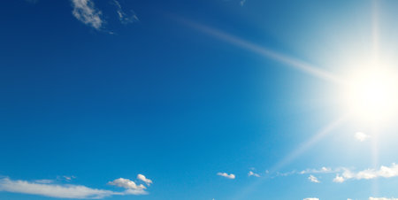 Bright sun on beautiful blue sky with white clouds.の写真素材