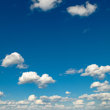 White fluffy clouds and bright sun on dark blue sky.