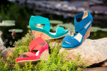 two pairs of green and red shoes and bag lay on the grassの写真素材