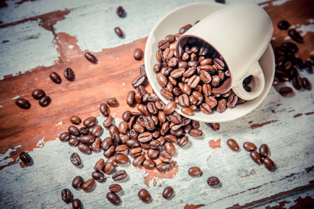 scattered grains of coffee in a cup on a wooden backgroundの写真素材