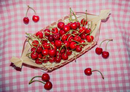 Ripe cherries in a basket on pink tableclothの写真素材