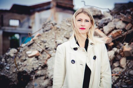 Blonde in the coat on the ruins of the house, beauty fashionの写真素材