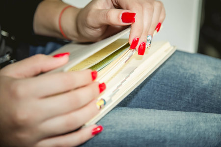 Red manicure, manicured hands, jeansの写真素材
