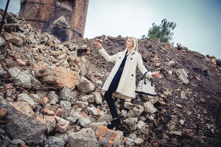 Blonde in the coat on the ruins of the houseの写真素材