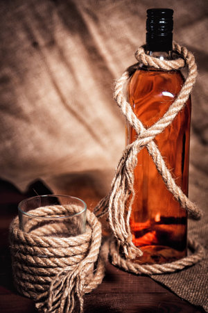 Whisky glass with ice, a bottle of whiskeyの写真素材