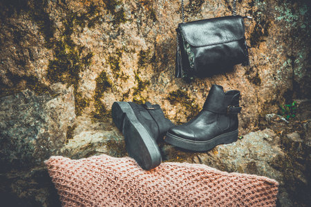 black leather boots and black handbag on granite and moss, female sodaの写真素材
