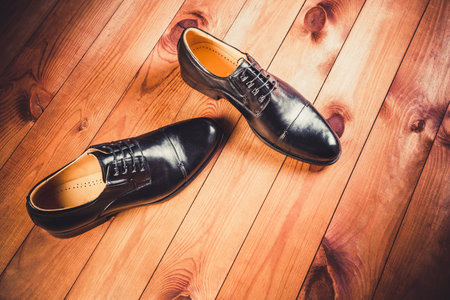 Black leather men's shoes on a wooden backgroundの写真素材