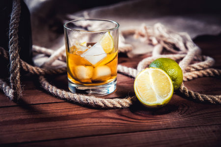 A bottle of whiskey, rum, brandy, lime on a wooden backgroundの写真素材