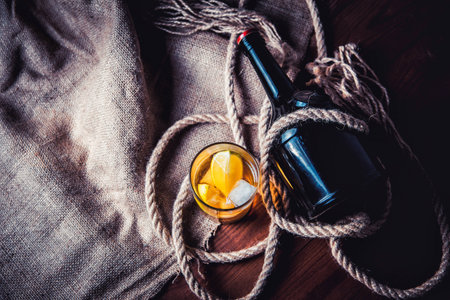 A bottle of whiskey, rum, brandy, lime on a wooden background