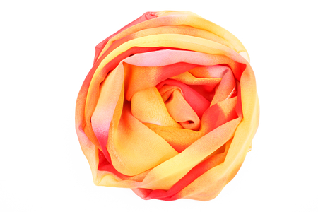 a red and yellow silk scarf is folded like a rose isolated on white backgroundの写真素材