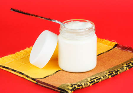 jar with yogurt isolated on red background. foods for a healthy dietの写真素材
