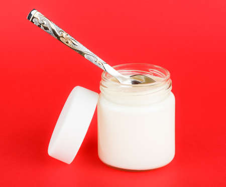 jar with yogurt isolated on red background. foods for a healthy dietの写真素材