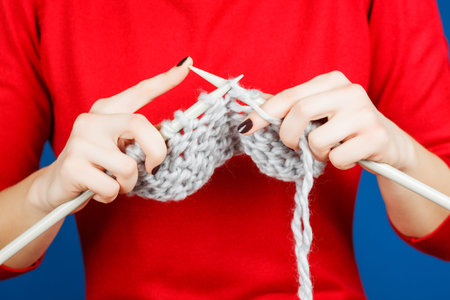 Knitting of woolen yarn. Needlework in the hands of women isolated on a blue background