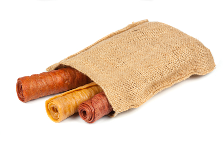 Candied fruit twisted in roll in the linen bag isolated on white background. Homemade sweetness of dried fruit. Culinary dessert.の写真素材
