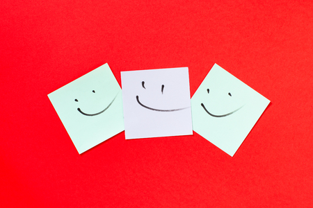 Smilies on paper for notes. Isolated on red background.の写真素材