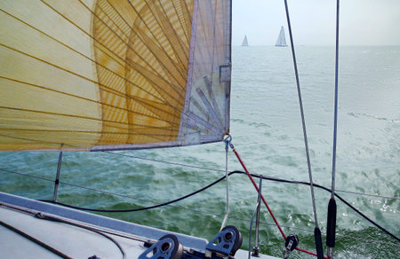 Sail against blue sky, sea and yachts